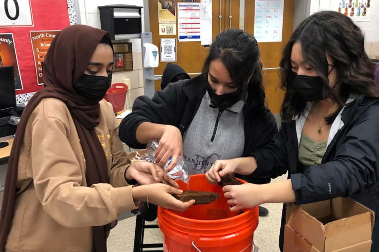 a group of three NxtGen conservationists taking part in vermicomposting