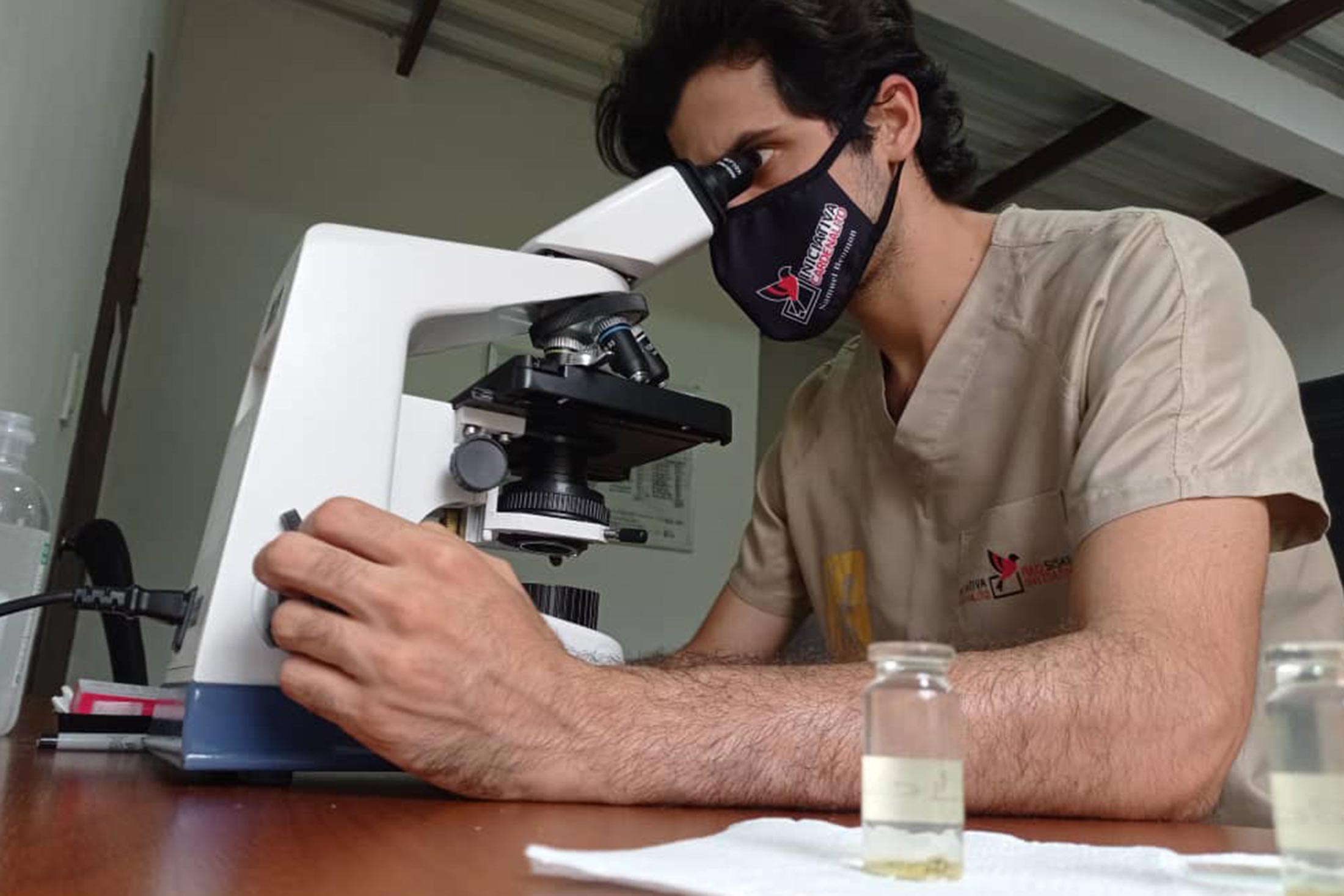 a scientist with the Red Siskin Initiative looks through a microscope