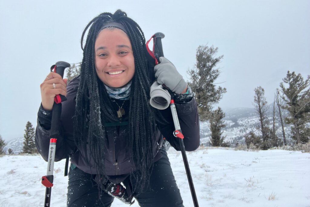 Conservation Nation Fellow Taylor Bland standing on skis holding ski poles and a spotting scope