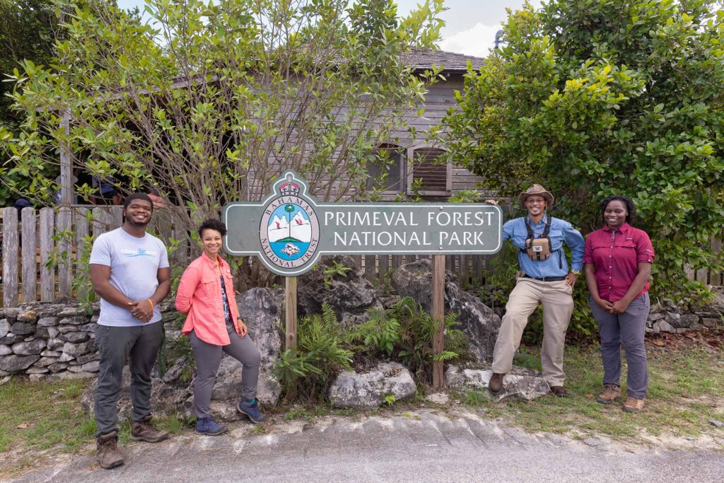 four adults standing near sign that reads Primeval Forest National Park