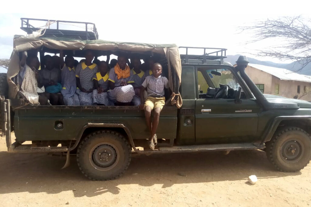 a group of school children in Kenya sitting in a green truck