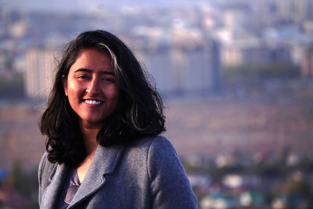 a woman posing while wearing a gray blazer