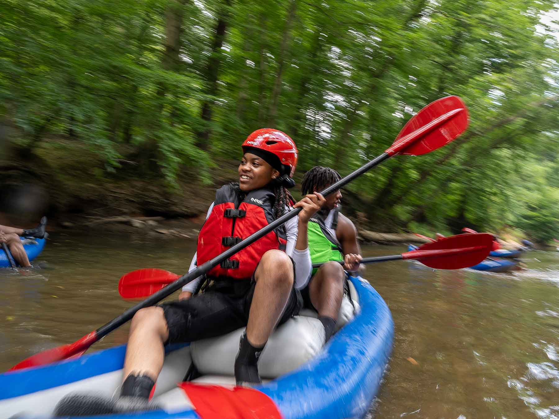 young people in a kayak going down a river