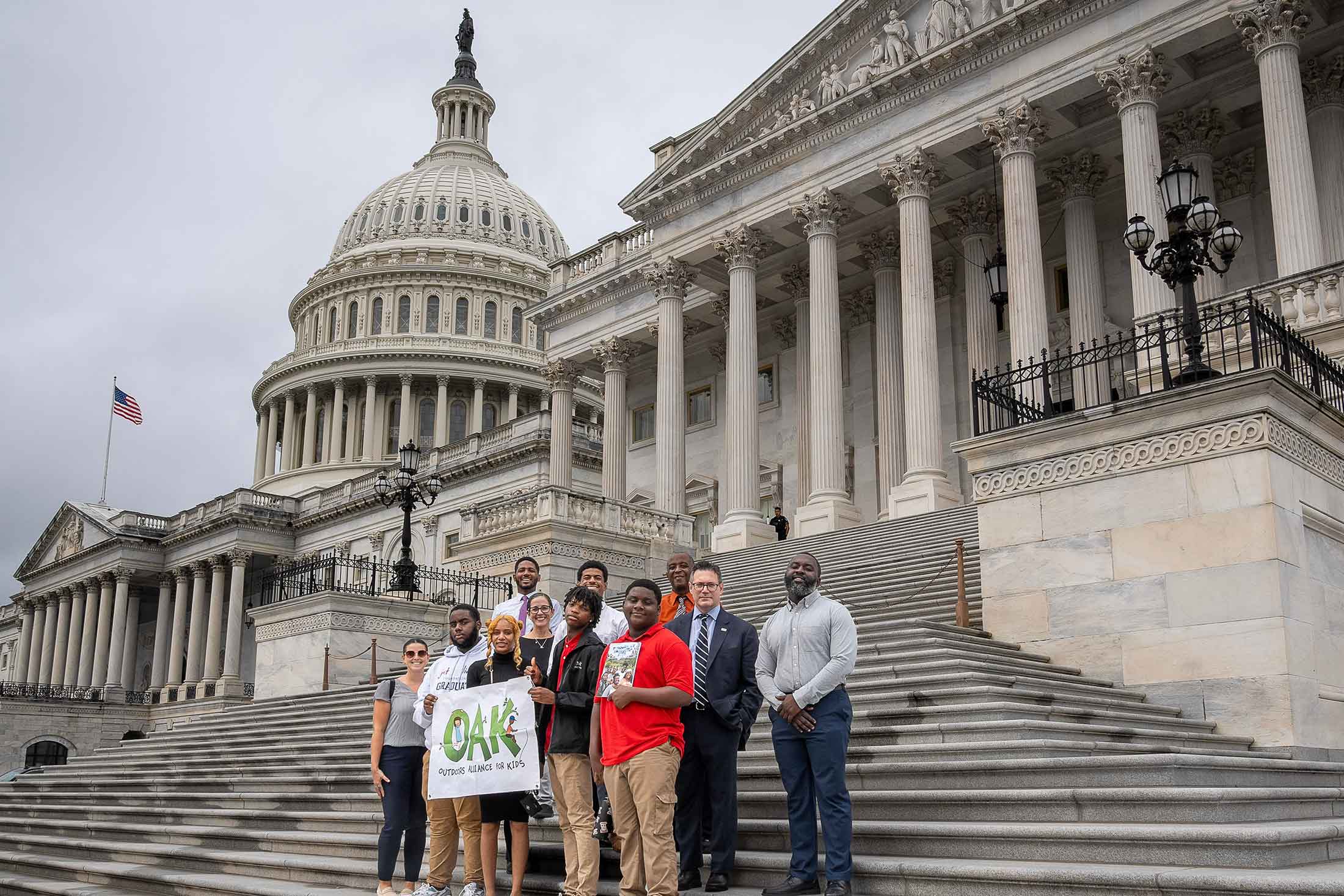 a group of teens and adults standing on the steps of the U.S. Capitol Building in Washington, DC