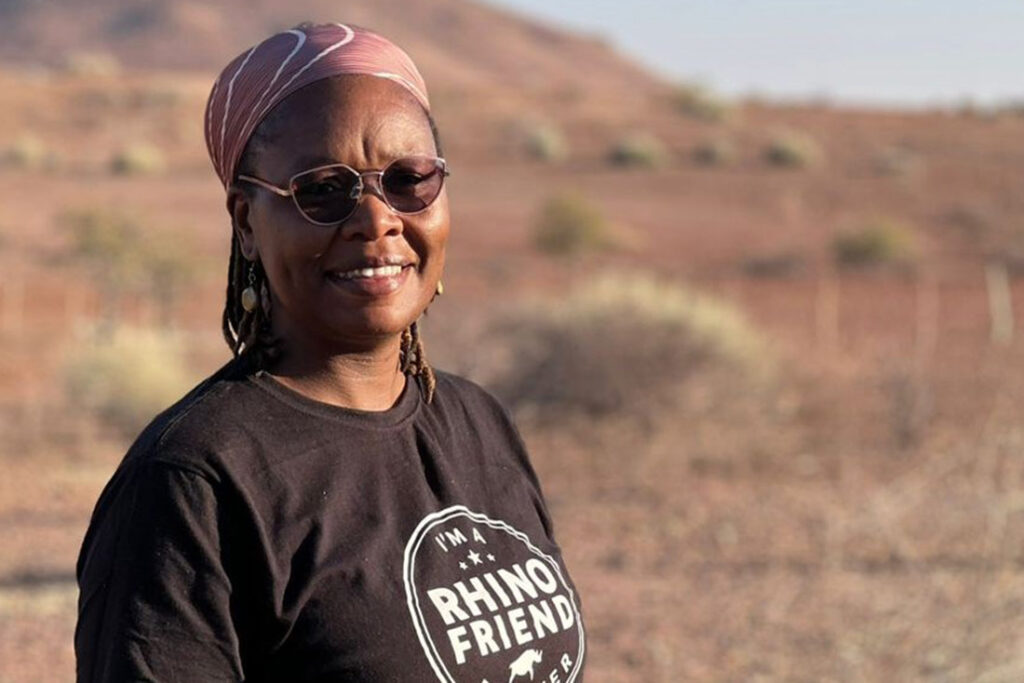 a Black woman smiling and wearing sunglasses and a t shirt that reads I'm a rhino friend