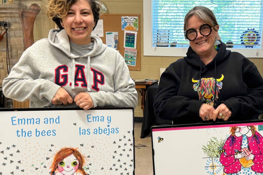 two adults in a classroom holding up a large illustrated book